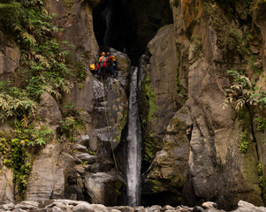 Group rappelling down a waterfall in Salto do Cabrito. Sao Miguel island in the Azores.