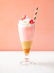 Strawberry caramel milk shake, smoothie, cocktail with whipped cream topping. Pink background. Close up.