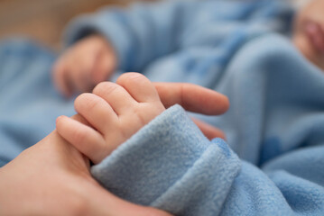 Close-up of a hand of a newborn baby holding mother's finger