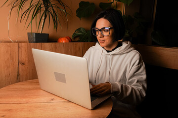 The open laptop symbolizes modern productivity. Resting her chin on her hands, a woman gazes...