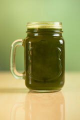 Green smoothie in a glass mason jar on wooden table