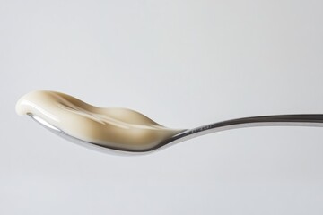 A spoonful of creamy, pale-yellow substance, possibly yogurt or custard.
