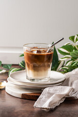 iced cold brew latte with ice cubes and a straw in a clear glass, showcasing creamy layers and rich coffee tones