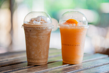 Close up glass of iced coffee frappe and ice fruit frappe on wooden table of a coffee shop summer terrace, menu photography.