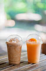 Close up glass of iced coffee frappe and ice fruit frappe on wooden table of a coffee shop summer terrace, menu photography.