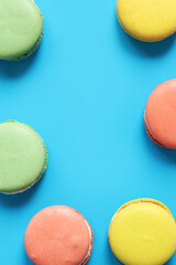 Macarons on blue bright background. Delicious pastries, flat lay. Food background. Sweets. Bright French macarons on blue background, top view. Assortment of colorful macarons