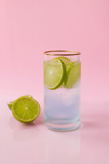 Gin tonic - cocktail based on blue gin and tonic with lime in a glass isolated on a pink background