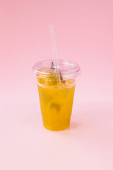 Peach lemonade in a plastic cup isolated on a pink background