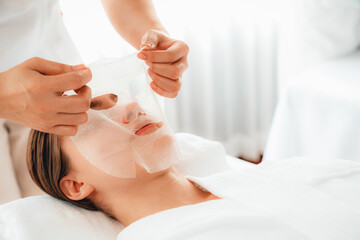 Serene modern daylight ambiance of spa salon, woman customer indulges in rejuvenating with facial skincare mask. Facial skin treatment and beauty cosmetology procedure for face. Quiescent