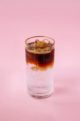 cold coffee ice tonic in a glass isolated on a pink background