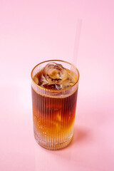 cold iced orange coffee in a glass isolated on a pink background