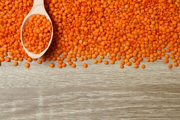 Red lentils in a spoon on a wooden background