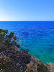 Scenic coastal view with vibrant blue ocean and rocky cliff under clear sky