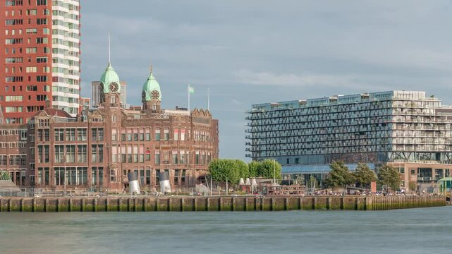 Timelapse of modern buildings with Hotel New York's historical facade in downtown Rotterdam. Former Holland-America Line HQ. People relax on the waterfront as boats pass by. Iconic architecture