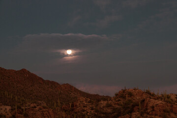 moon rising over the mountain in the clouds