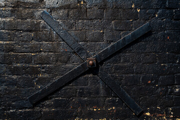Black painted wall anchor plate on a black painted brick wall