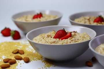 Healthy proso millet porridge topped with fresh sliced strawberries in a bowl