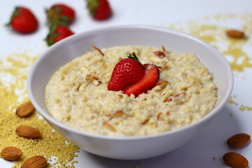 Healthy proso millet porridge topped with fresh sliced strawberries in a bowl