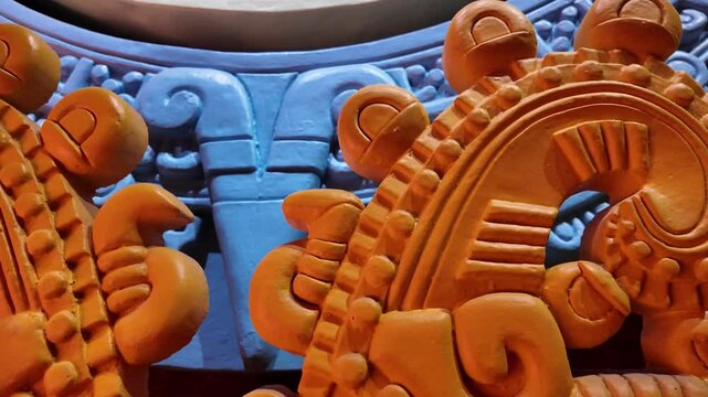 A piece of art with a spiral design. The spiral is orange and has a black center. The piece is on a table