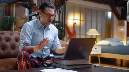 Caucasian businessman in pajama and shirt speaking with client on video call on laptop while Japanese wife waving and joining conversation