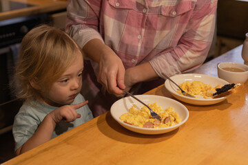 Boy pointing at plate of food while having breakfast with his mother