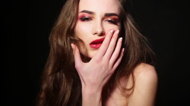 Beautiful model smearing lipstick on her face. Fashion model with messy lipstick. Beauty portrait with smeared lipstick. Sensual woman smudging red lipstick. Sensual girl with smeared makeup on lips.