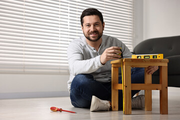 Man using level tool while repairing wooden stool at home