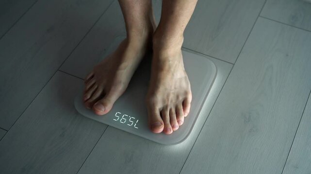 Measuring weight.
A man on scales.
A man weighs himself on scales.
The problem of excess weight and the topic of losing weight