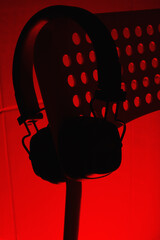 Close up of large bluetooth headphones on perforated table in yellow light at night.