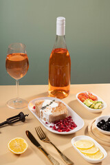 A bowl of tasty tuna and vegetable salad, a glass of wine, a modern naturism on a coloured table, flat plan. Place for text
