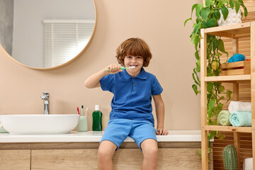 Cute boy brushing his teeth on countertop in bathroom © New Africa