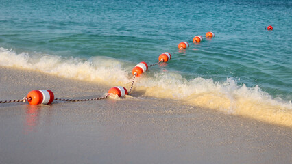 buoy rope floating in ocean waves. turquoise sea water in background. reflection in the sand and tide. maritime caution hazard safety backdrop. swimming education economy design element.