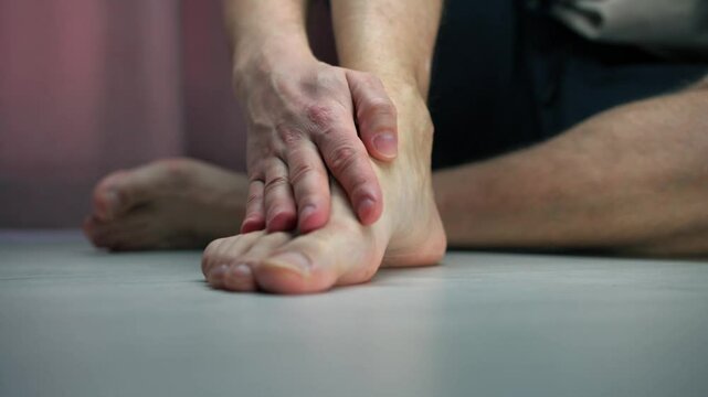 A man massages his leg.
A sore leg.
A leg injury.
A bruise on the leg.
Suffering from pain in the leg.
A man sits on the floor and strokes his sore leg.