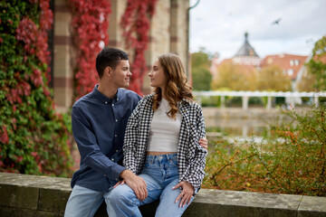 Fototapeta premium Young Cute Female Hugs Boyfriend. In Autumn Outdoor. Lovers Walking in Park. Attractive Funny Couple. Lovestory in Forest. Man and Woman. Cute Lovers in the Park. Family Concept. Happy Couple.