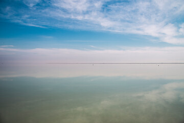 Bushehr Mirror: Calm waters reflect an expansive sky, revealing nature’s serene and timeless...