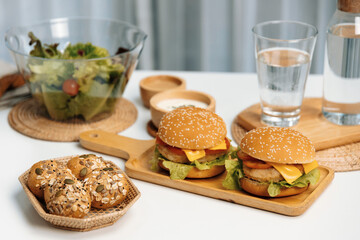 Tasty food in double meat hamburger, salad, wholegrain bun on meal cooked by homemade serving on white table. Preparing special dish to lay out photo shooting menu list's restaurant or cafe. Infobahn.