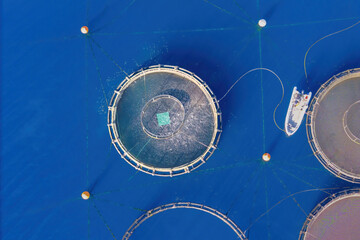 Service feeding boat on offshore aquafarming fish farm in sea for cultivation fish. Aerial view