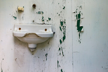 Broken Sink Against a Wall with Peeling Paint