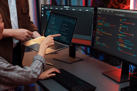 Serious of IT developers discussing intelligent website development coder system running data online two screens with laptop showing information network at neon light room at modern office. Infobahn.