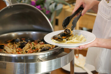 Woman taking food from a buffet line	
