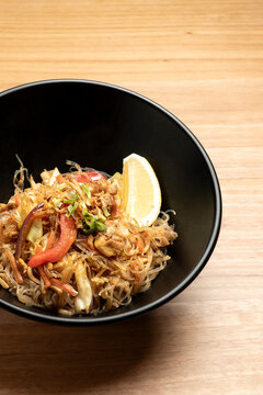 Steaming pancit bihon, a filipino noodle dish, served with chicken, vegetables, and a lemon wedge