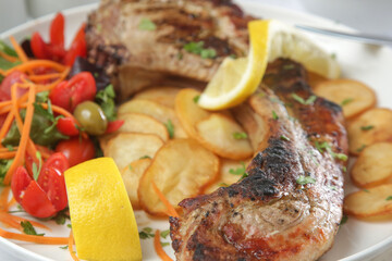 Pork chop with rib bone served with potato and green salad