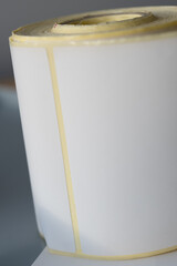 A close-up view of a tightly rolled blank adhesive label strip with rectangular shapes, commonly
