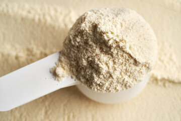 Whey protein powder in a measuring cup, close up