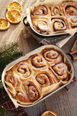 Homemade cinnamon rolls in two baking pans on a wooden table