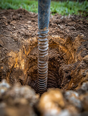Obraz premium Close-up of earth auger drilling hole in soil for construction