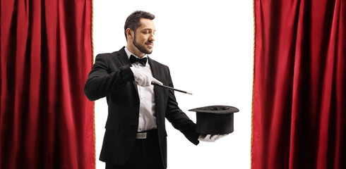 Magician performing a trick with a magic wand and a top hat on stage © Ljupco Smokovski