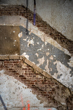 Exposed brick and peeling plaster on a weathered interior wall