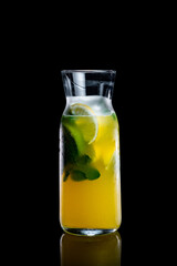 Homemade lemonade with lemon and mint in a glass bottle on a black background