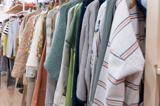 A colorful array of clothing on a rack in a cozy clothes shop